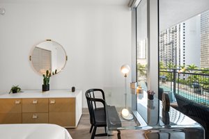A modern room with a round mirror, a chair, and a table with a plant on it.